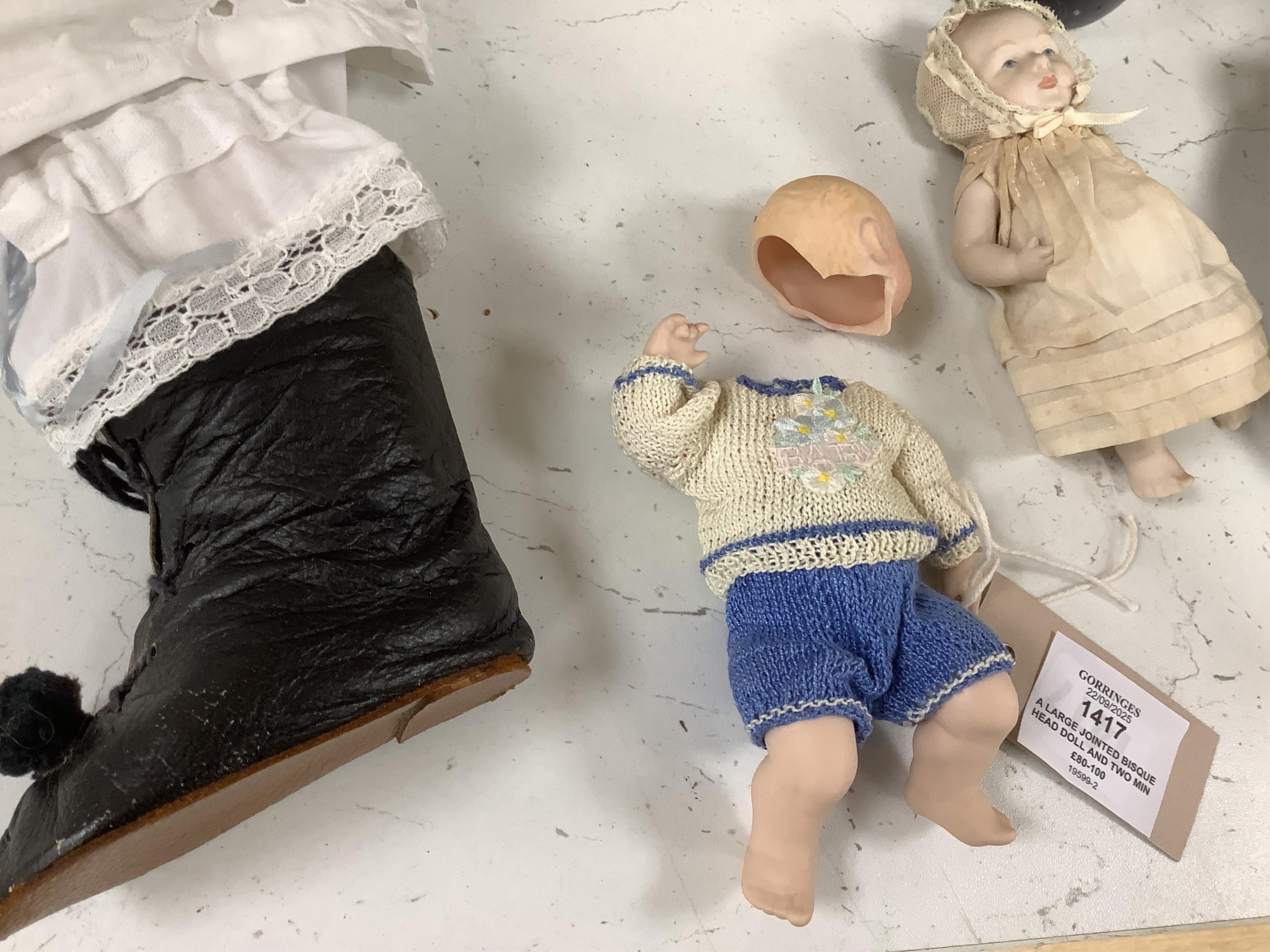 A large jointed bisque head doll and two miniature bisque dolls